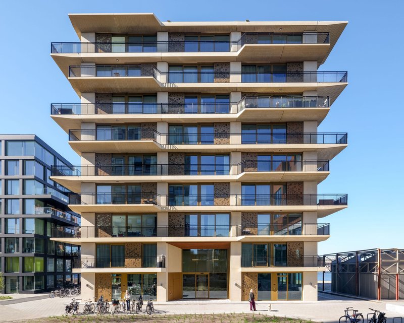 Frontal view of the multi-story residential facade with deep cantilevered balconies and bicycles parked at ground level