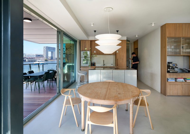 Open-plan kitchen and dining area with timber cabinetry and sliding doors to the balcony