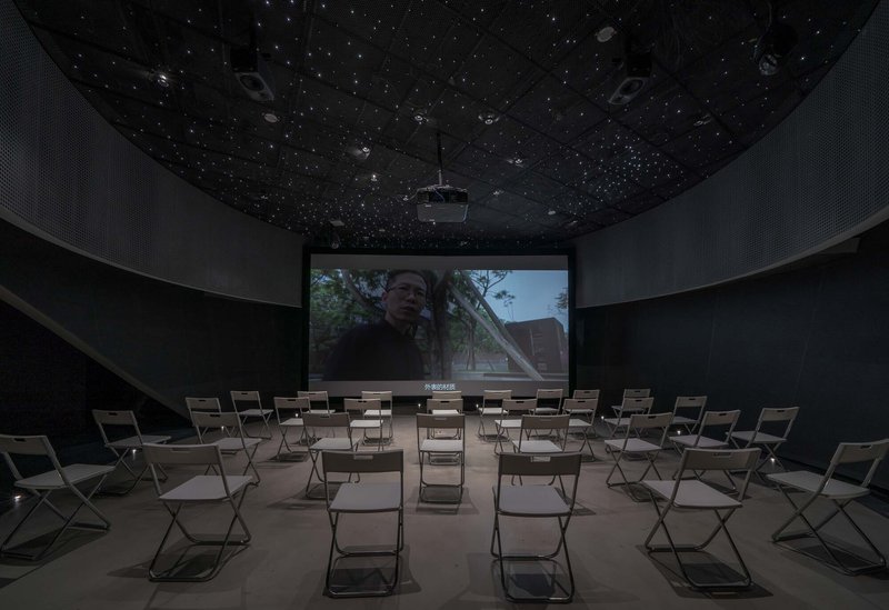 Screening room with folding chairs facing a projection under a perforated starfield ceiling