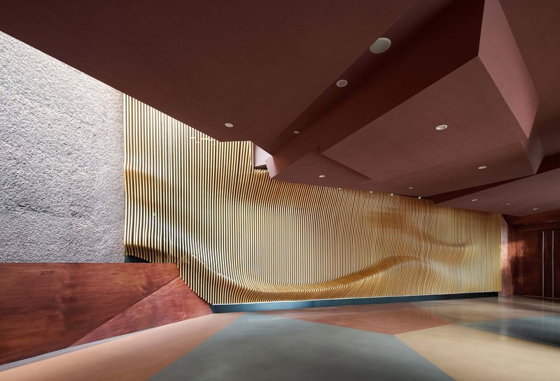 Interior lobby with vertical timber screen wall and angular red-brown ceiling planes