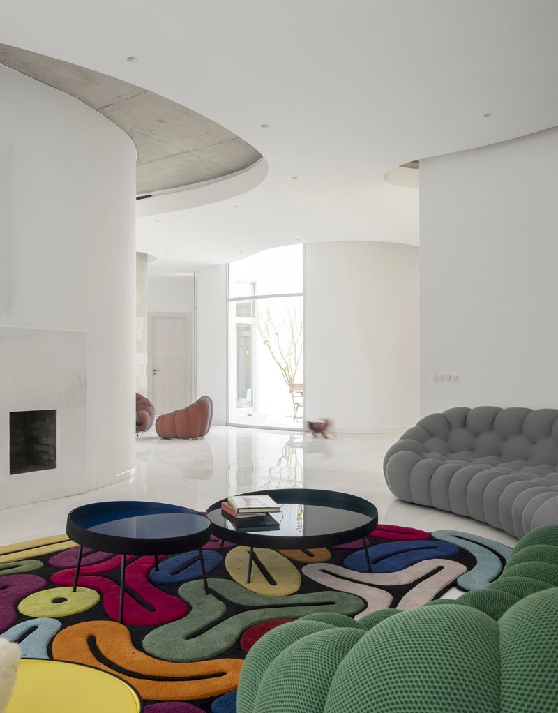 Living room with curved concrete ceiling forms and a patterned rug under bright daylight
