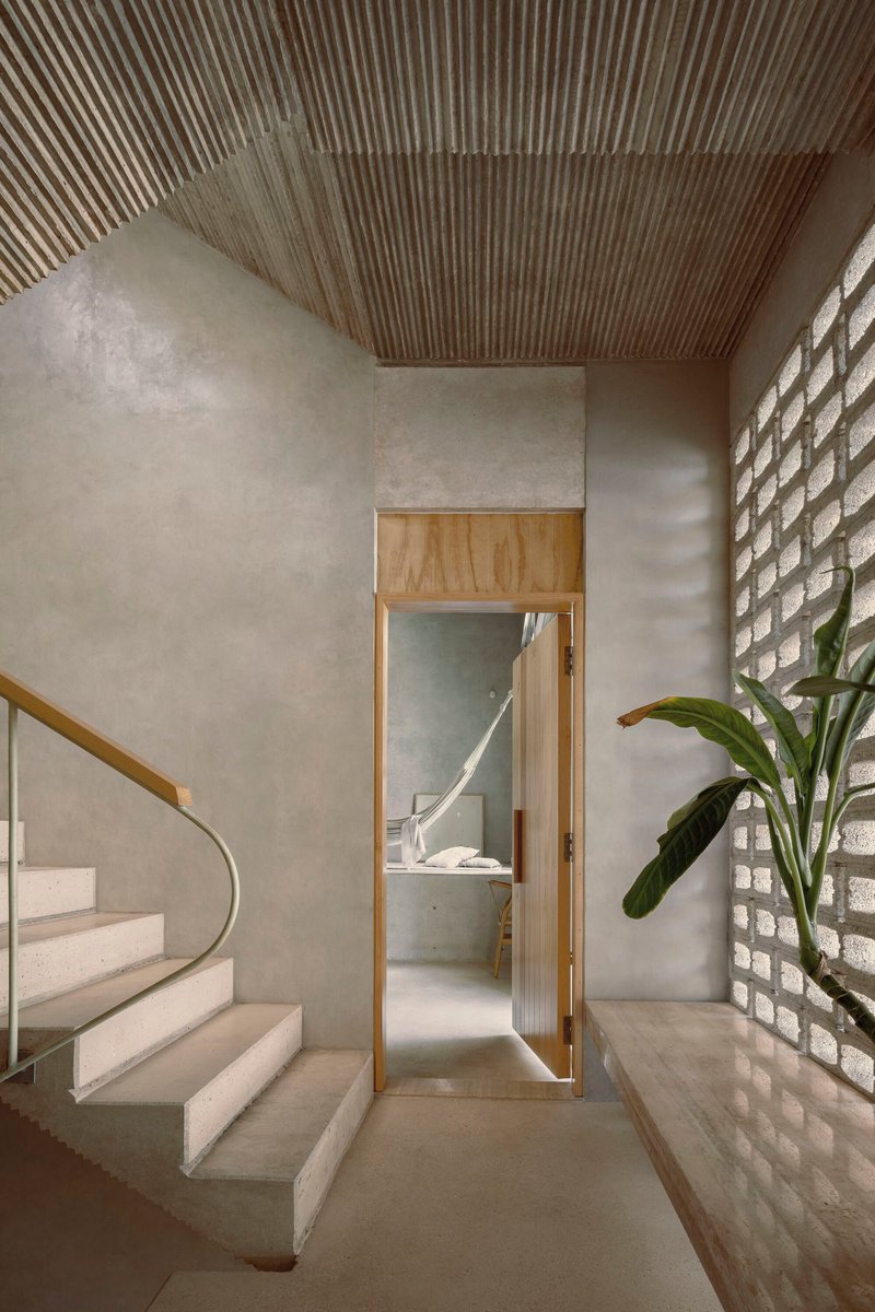 Concrete staircase with timber-framed doorway, corrugated ceiling and glass brick wall filtering daylight