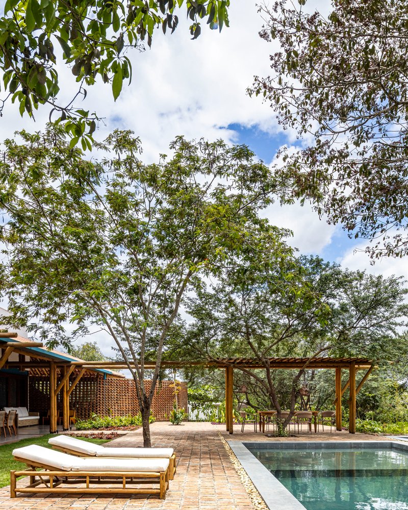 Pool deck with brick pavers and wooden loungers framed by mature trees and lattice screening
