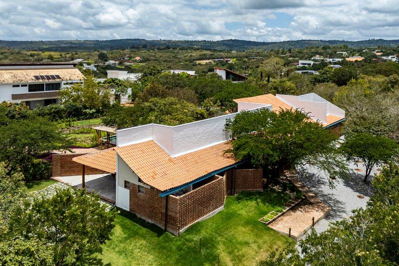 Aerial perspective of interlocking orange tile roof volumes with perforated brick screen and courtyard