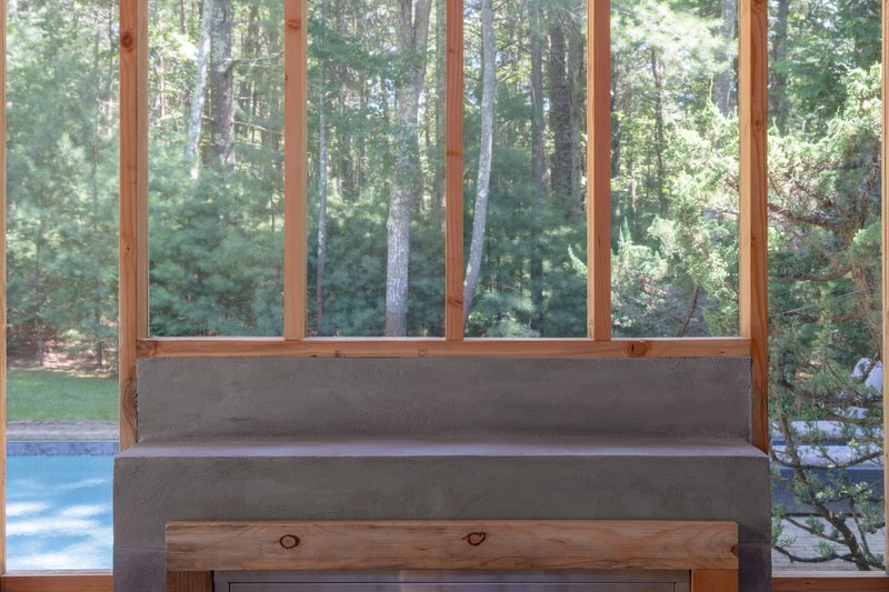 Built-in concrete bench with timber frame window overlooking forest