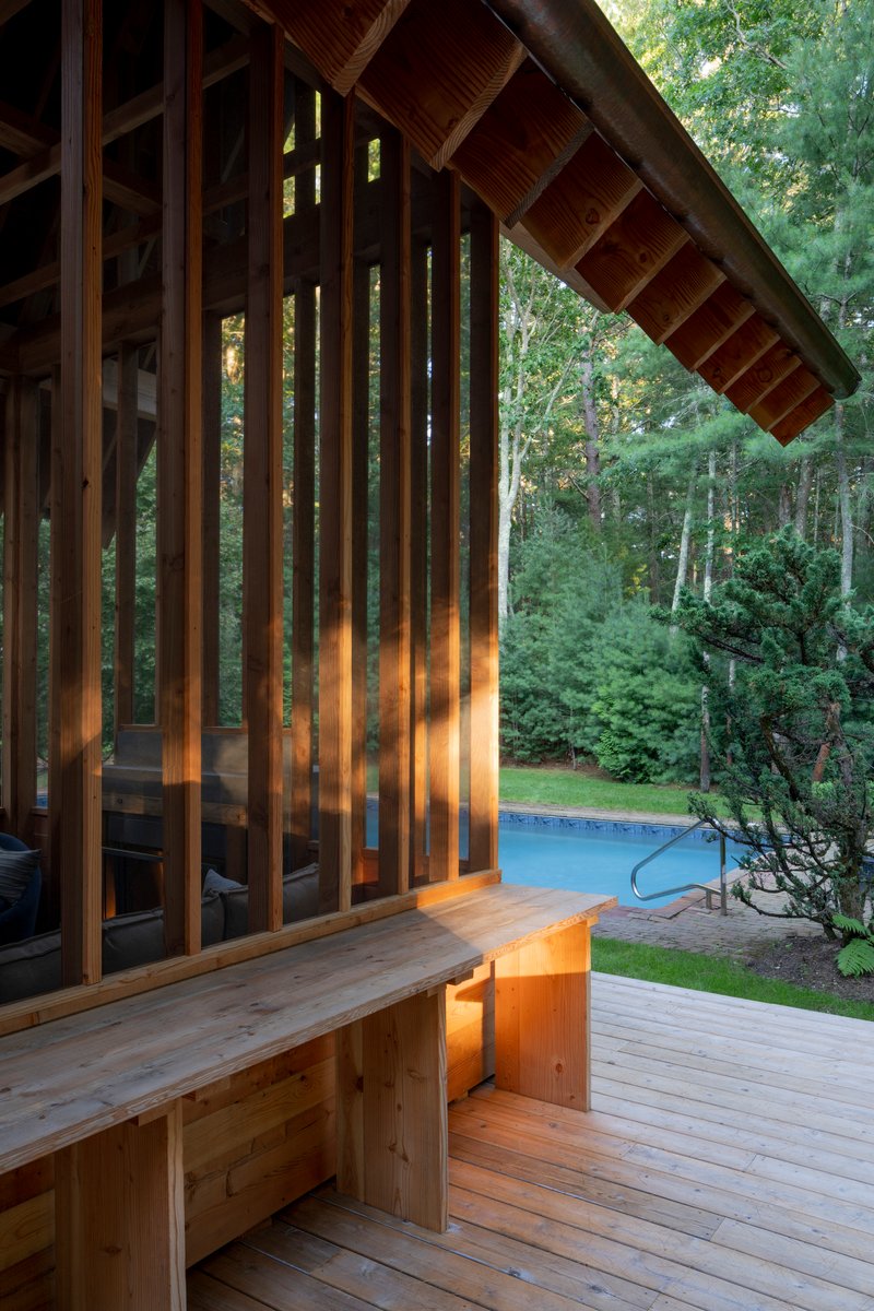 Corner detail of the vertical timber screen with built-in bench at dusk beside the pool