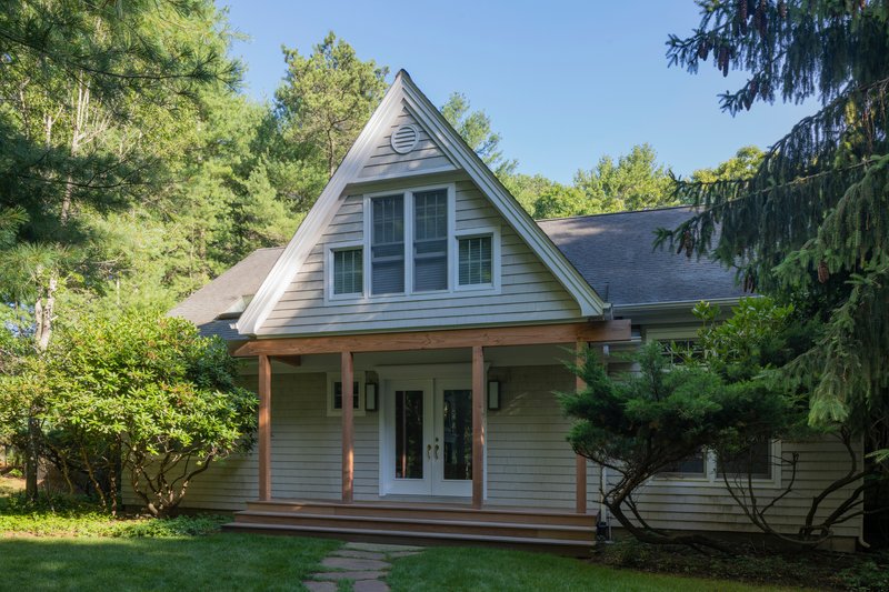Front porch with timber columns and triangular gable vent beneath a clear summer sky