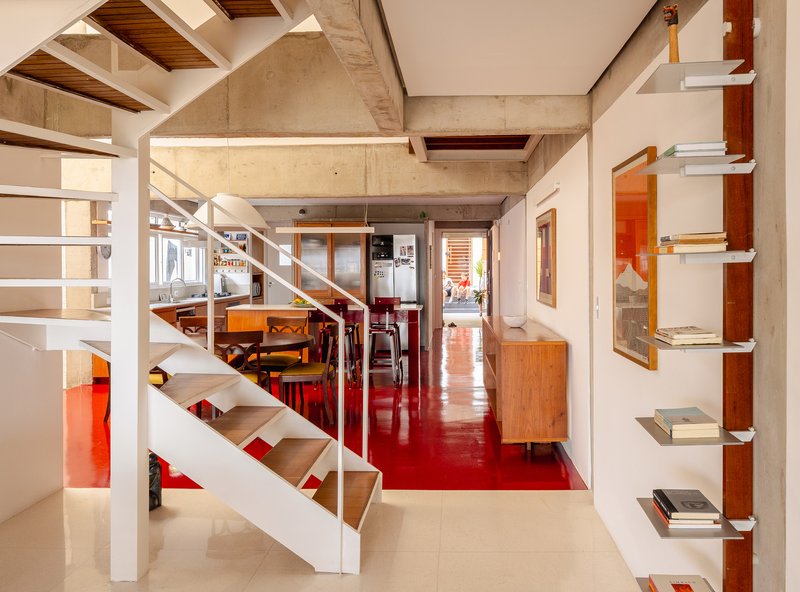 Mezzanine level view showing white steel staircase, red flooring and exposed concrete ceiling with timber insets