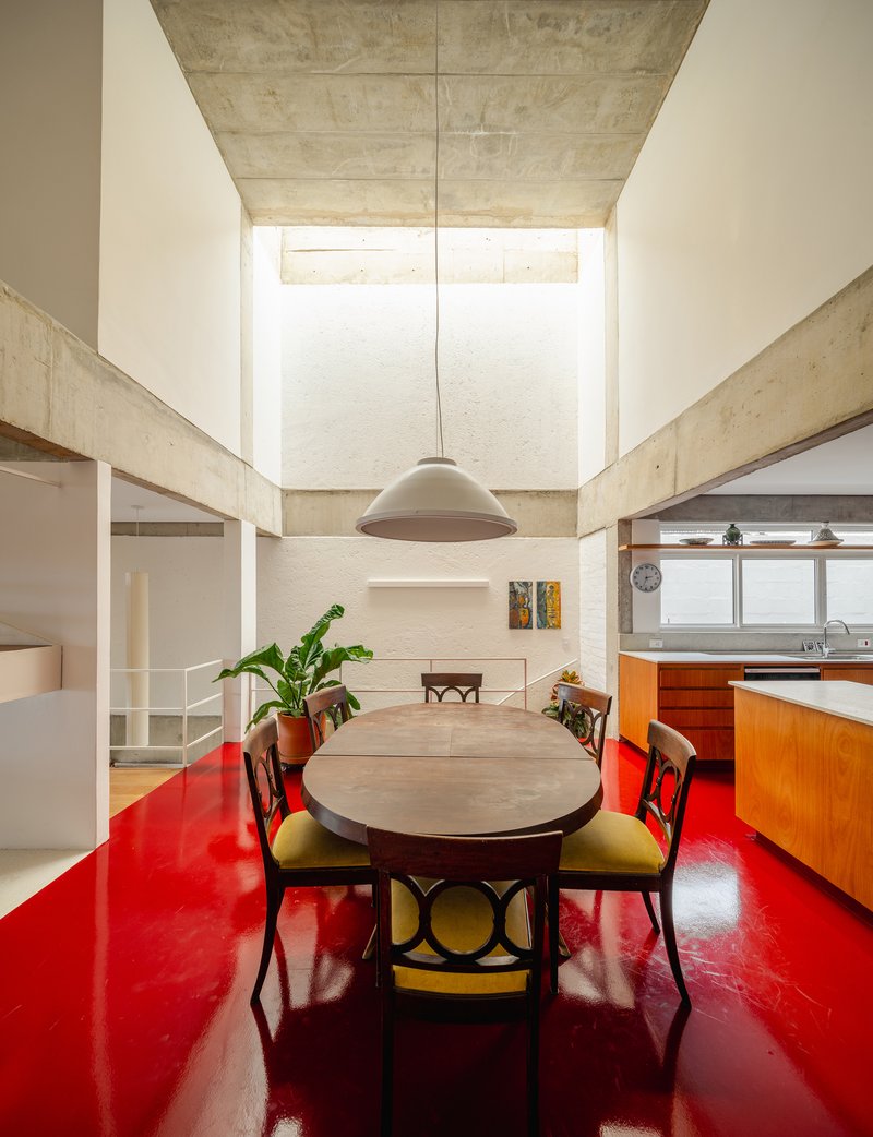 View toward the dining table under a tall clerestory window framed by concrete ceiling