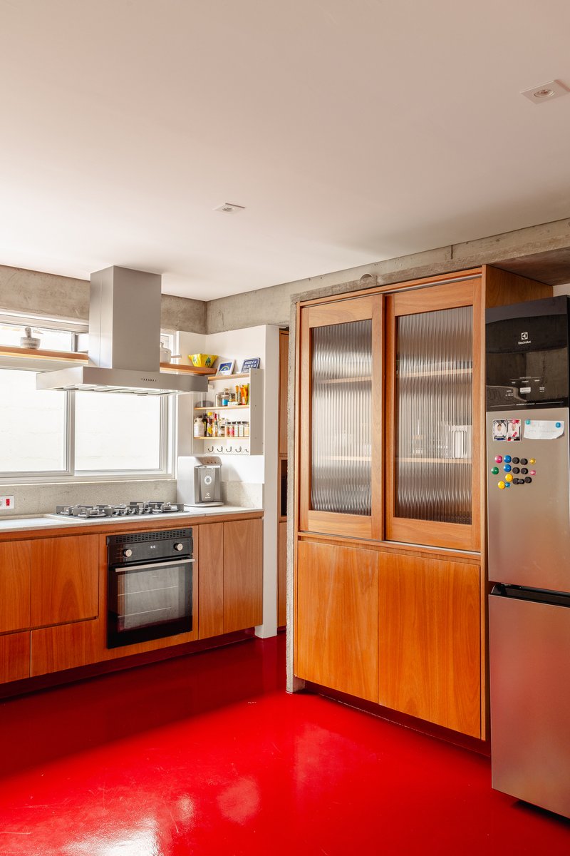 Kitchen with wood cabinetry, ribbed glass cabinet doors, and red resin floor