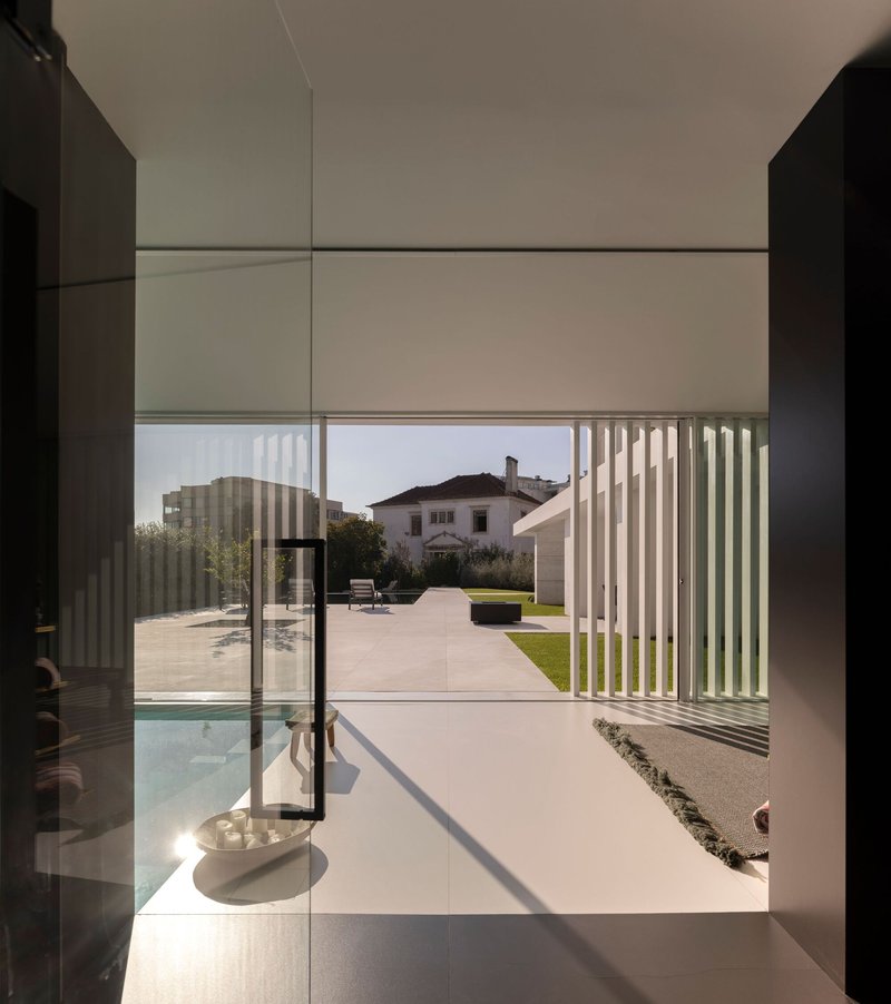 View from interior through floor-to-ceiling glass doors to the garden and slatted pergola beyond