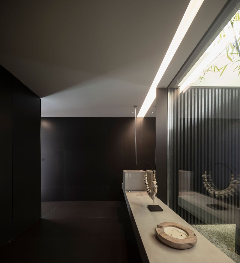 Interior hallway with clerestory skylight illuminating a black wall and white stone ledge displaying objects