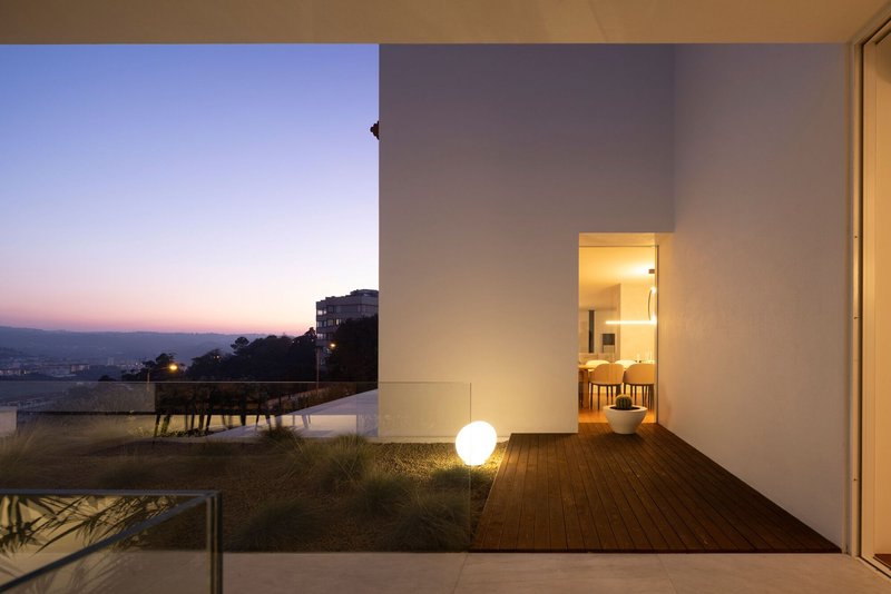 Timber deck terrace with globe lighting and a framed interior view at twilight