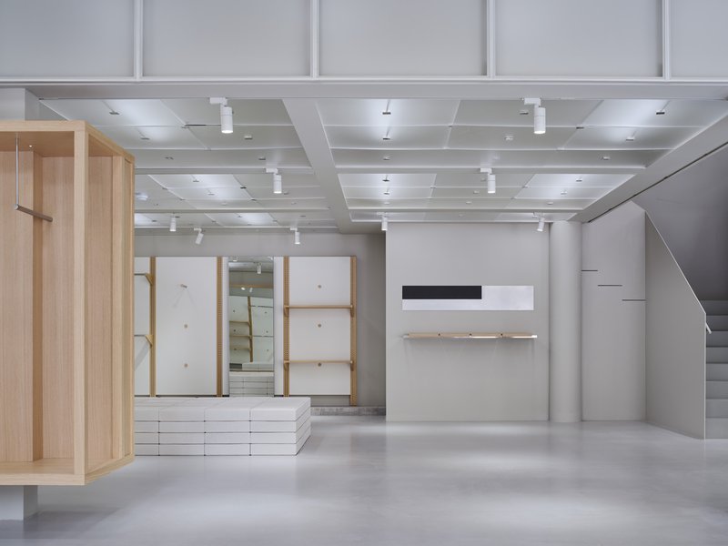 Interior view showing light wood framed display niches, white shelving, and cofferred ceiling with pendant lighting