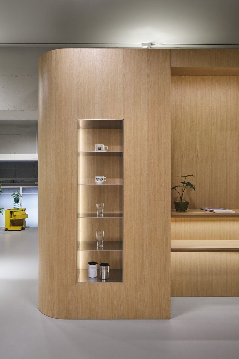 Curved light wood volume with vertical display niche containing glassware and ceramics