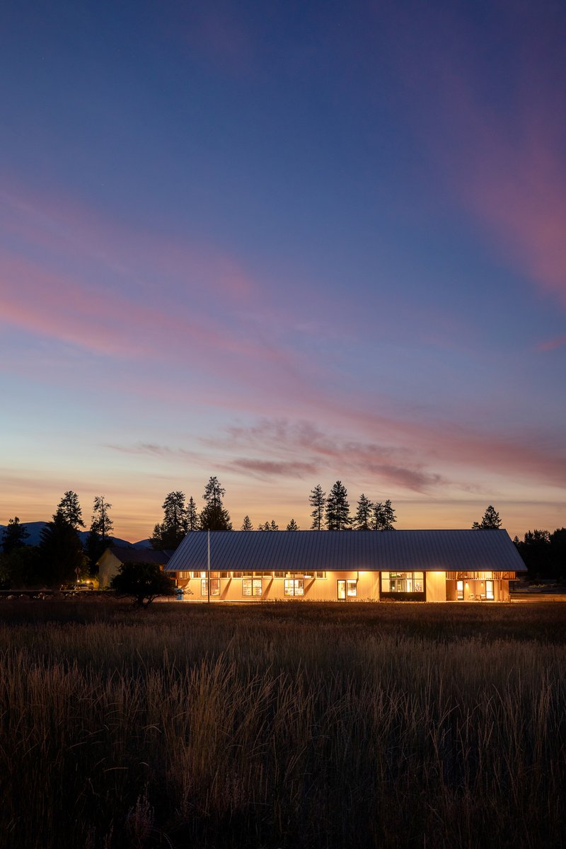 Distant view of the illuminated library across a meadow at sunset with pink and blue sky