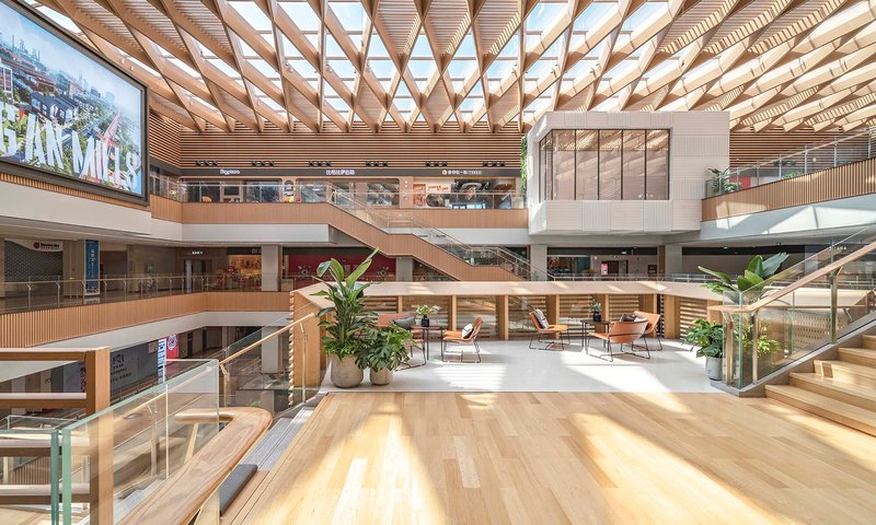 Multi-story atrium with timber lattice ceiling, interconnected walkways, potted plants and timber floor terraces