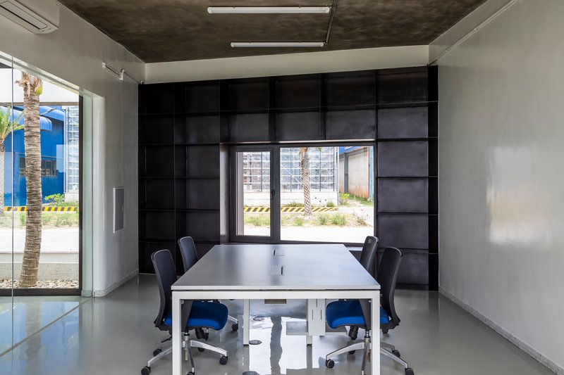 Conference room with black paneled wall and central framed window overlooking a palm tree courtyard