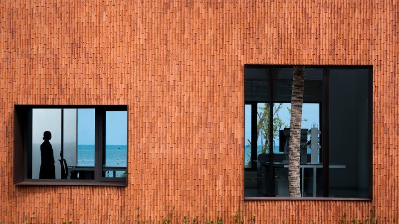 Exterior view of vertical terracotta brick facade with two offset window openings