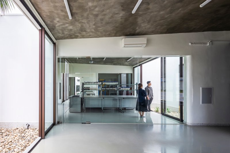 Interior corridor with polished concrete floor and glass-enclosed laboratory space with two figures in conversation