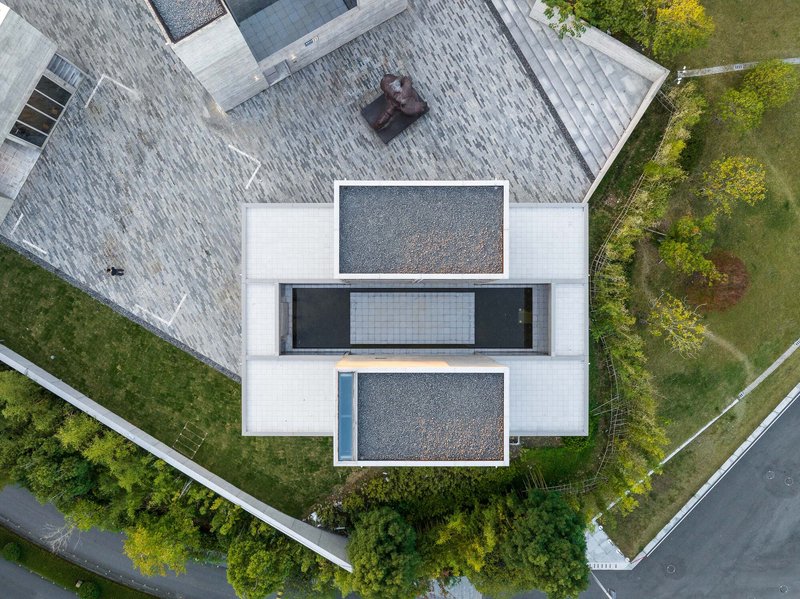 Drone view showing stacked terraces with gravel surfaces and glazed openings between shingled roofs