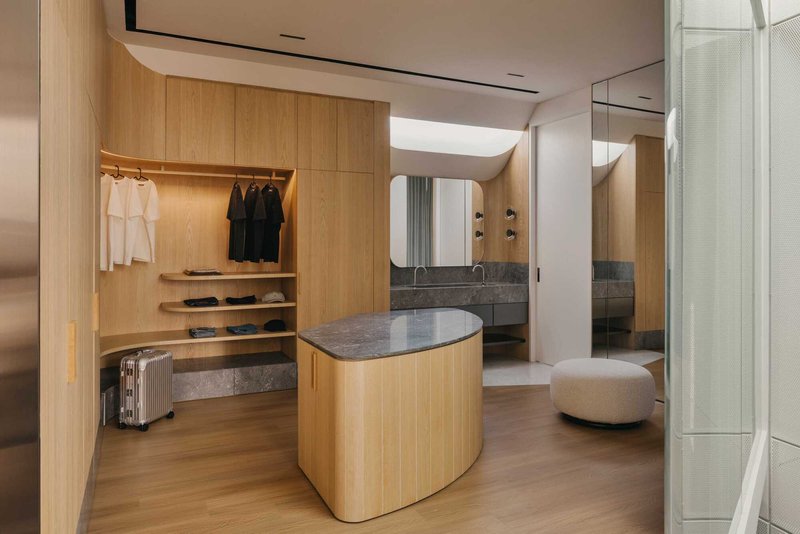 Dressing room with open timber wardrobe shelving and central island with stone countertop
