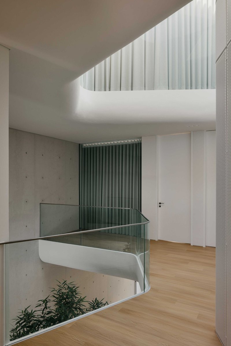 Balcony overlooking the central void with glass balustrade and vertical green curtains behind