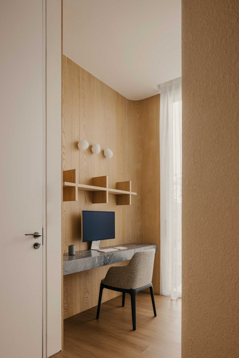 Built-in timber desk nook with floating shelves and three wall hooks in soft daylight