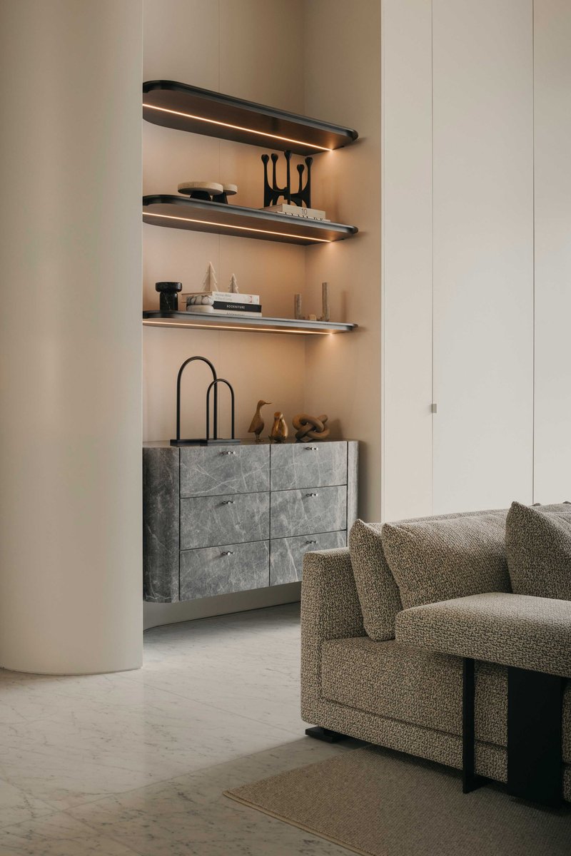 Living room niche with backlit floating shelves above a grey stone credenza and rounded column