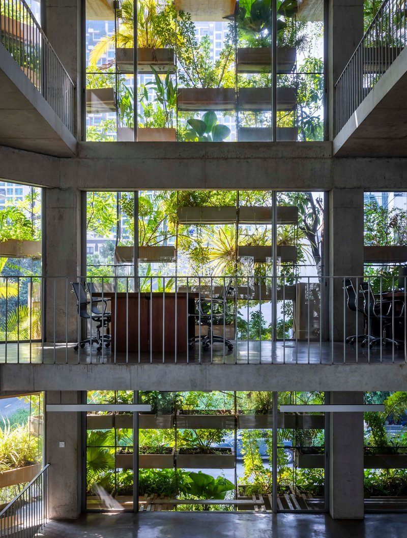 Vertical view through the atrium showing three levels of planted concrete slabs and metal balustrades