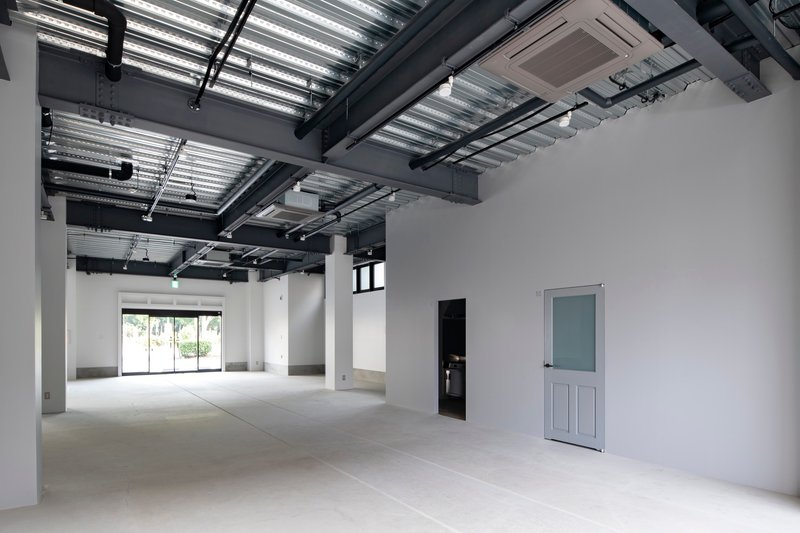 Interior space with exposed structural ceiling and white partition wall under ambient daylight