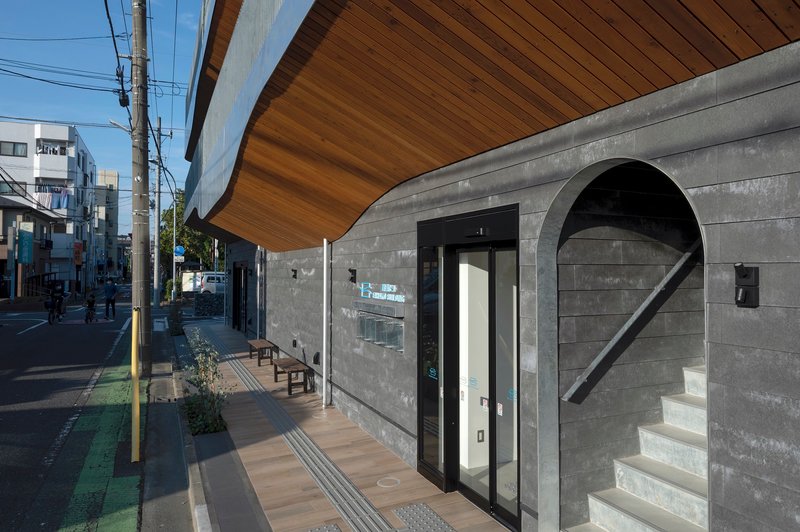 Street level entrance with concrete block wall, arched opening with stair, and overhanging wood soffit