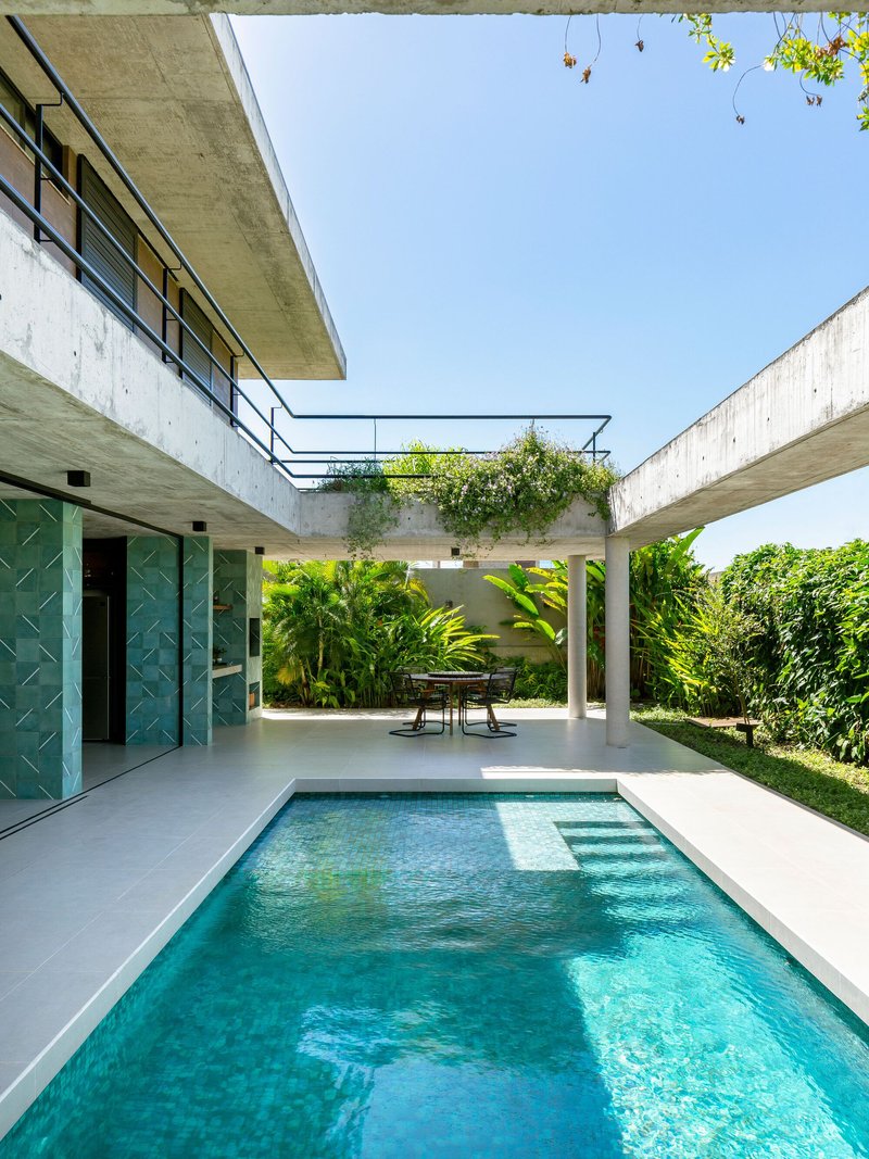 Pool terrace framed by concrete beams and planted green roof connecting two wings of the residence