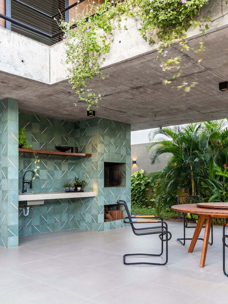Outdoor kitchen with turquoise relief tile backsplash under concrete soffit with cascading vine from above