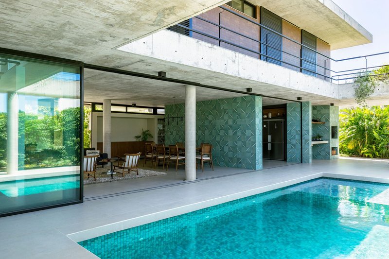 Courtyard pool with turquoise sliding panels and open-air dining space under concrete canopy and upper balcony