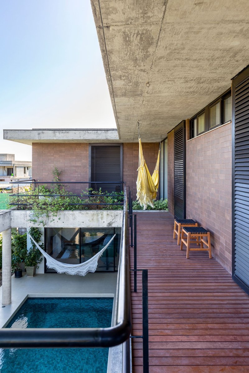 Upper terrace with timber decking, louvered screens, hammock below, and planter boxes along the concrete overhang
