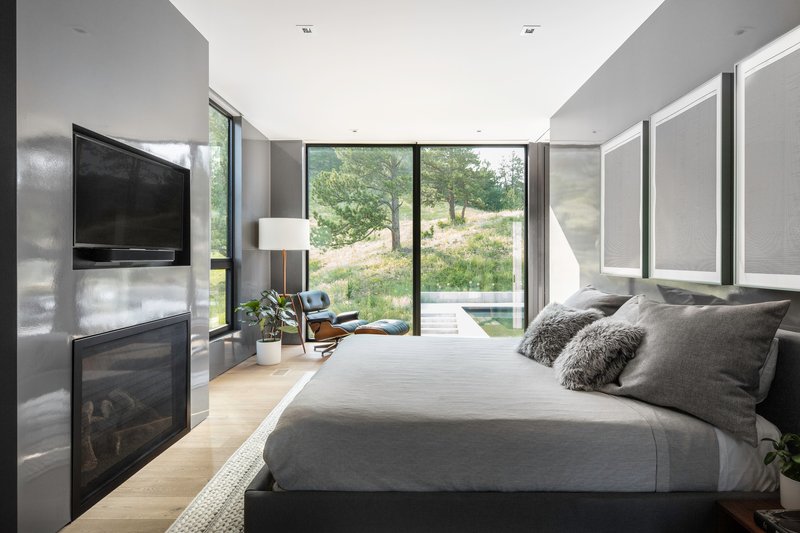 Bedroom with floor-to-ceiling glass doors opening to a grassy slope under afternoon light