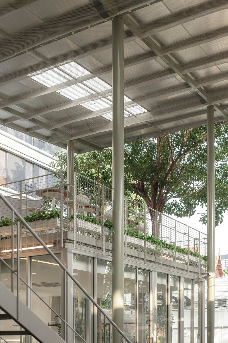 View of the steel staircase and mesh-clad balconies beneath the corrugated canopy with skylight panels