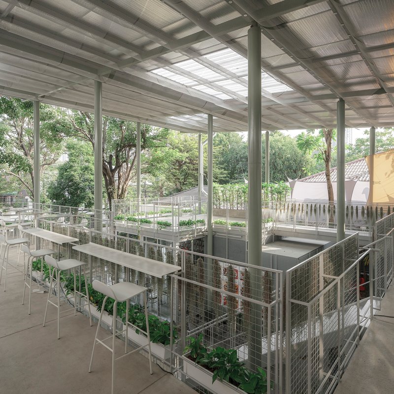Upper level terrace with wire mesh railings, white bar seating and skylights in the corrugated metal roof