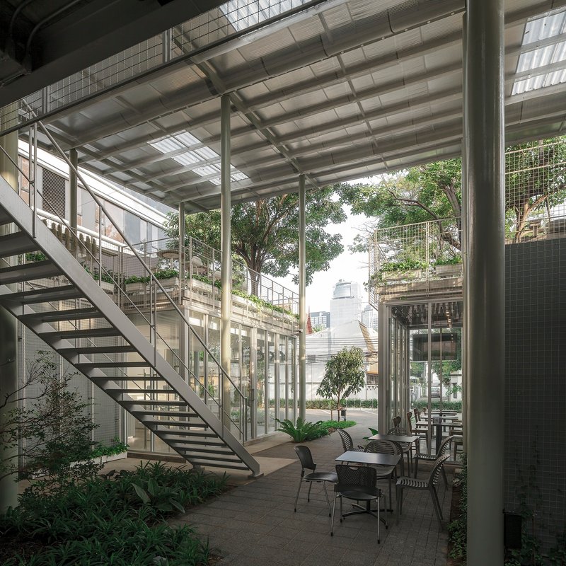 View across the courtyard showing the open-tread staircase, steel columns and planted ground-level terrace
