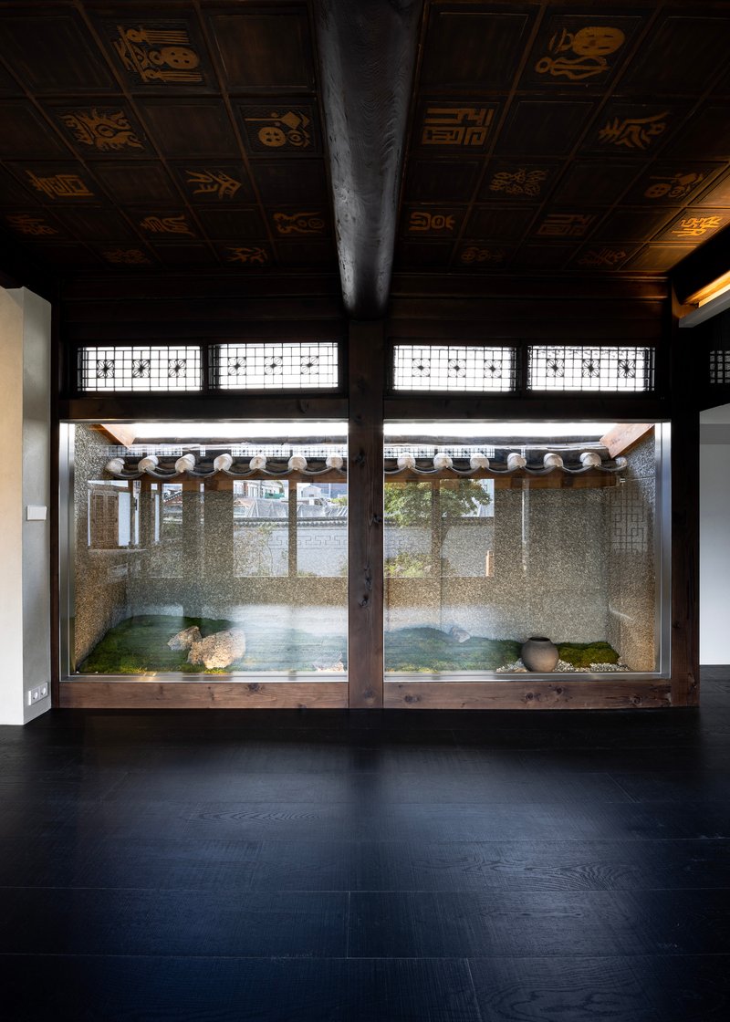 Interior view through latticed windows to a gravel courtyard with traditional tiled roof overhang