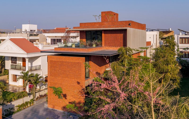 Stacked brick volumes with patterned screens and cantilevered roof plane surrounded by flowering trees