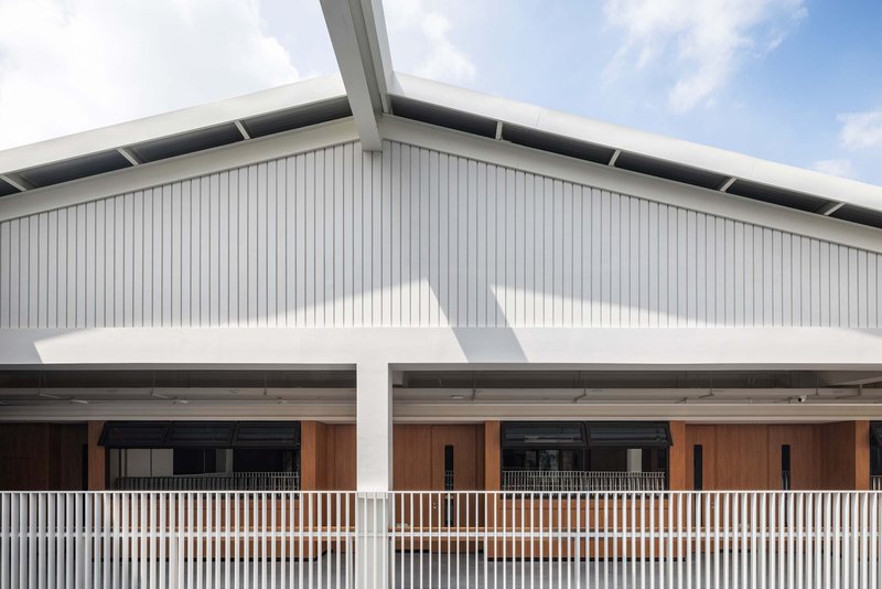 Gabled roof with vertical metal cladding above a covered walkway with white vertical balusters