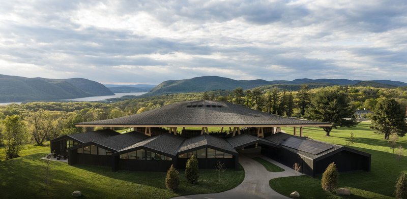 Aerial view of the multi-lobed green roof set within a manicured lawn with mountains and water beyond