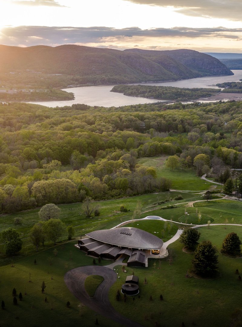 Drone view of the compound with curved access road and circular pavilion at golden hour