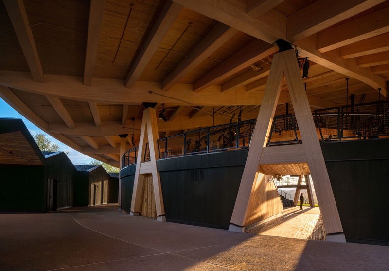 Covered colonnade with exposed timber beams and A-frame columns casting afternoon shadows on concrete
