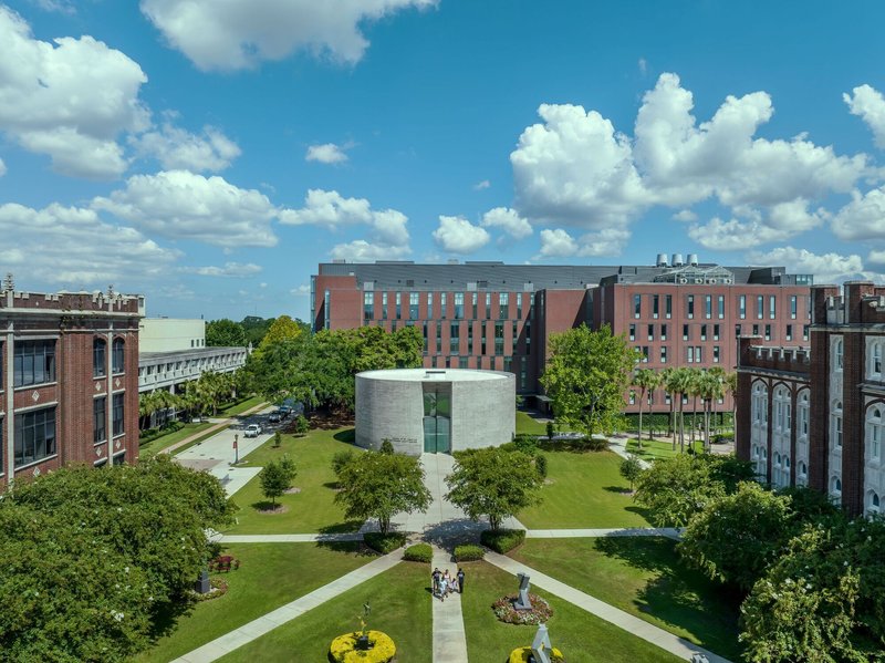 Aerial view of the circular chapel set within a campus quadrangle under summer clouds
