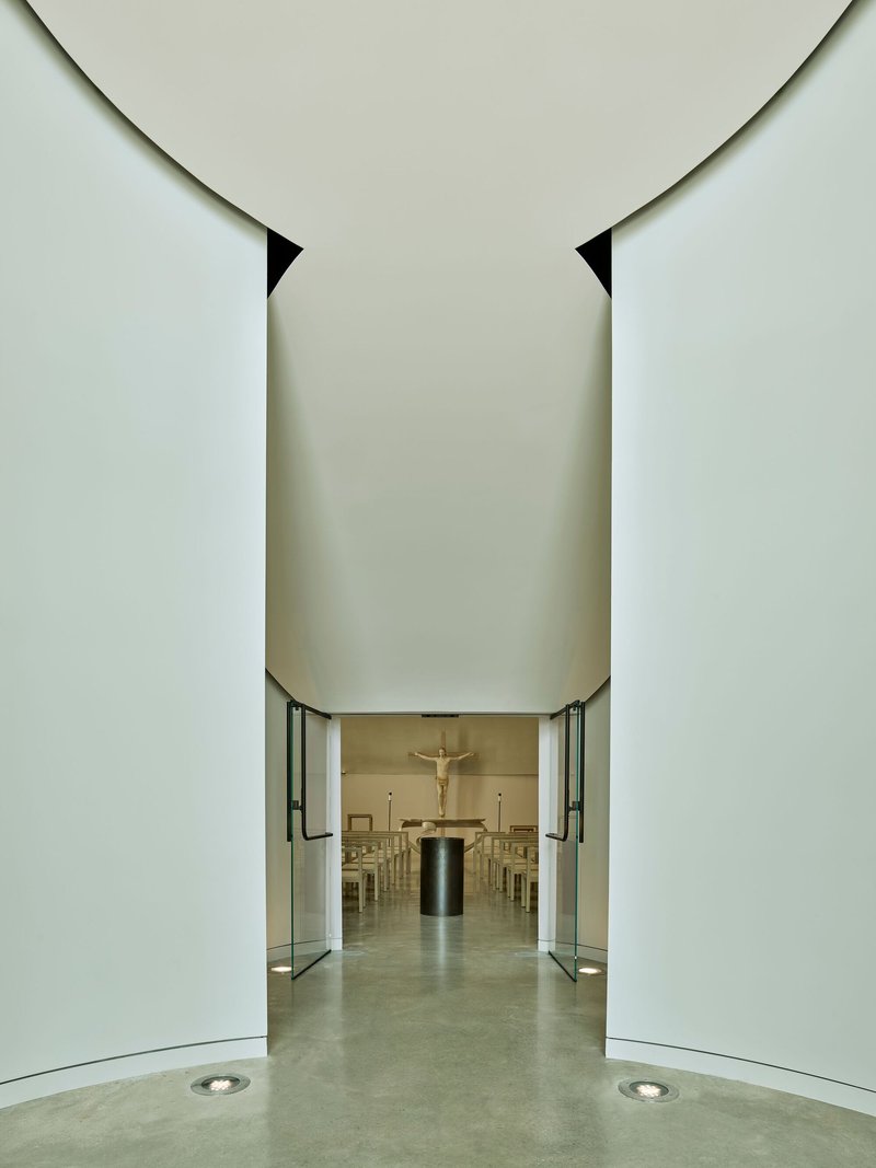 View through the central entrance corridor toward the chapel altar with glass doors open