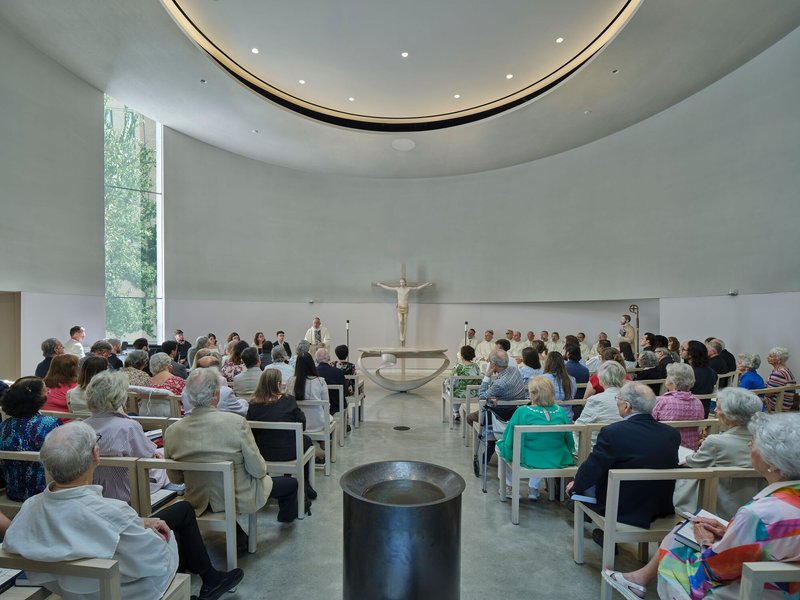 Congregation seated in the round sanctuary during a service beneath a circular skylight