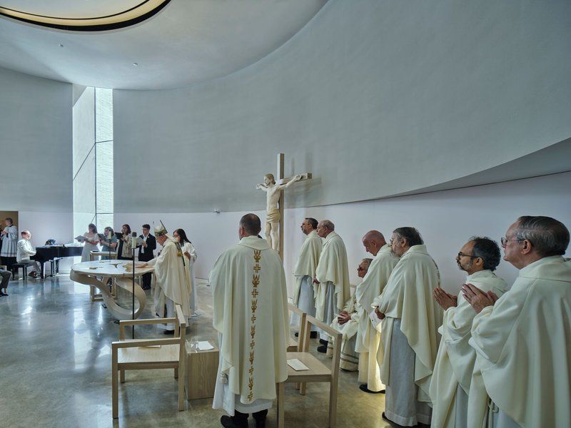 Clergy gathered around the altar during a ceremony under the domed ceiling with vertical window